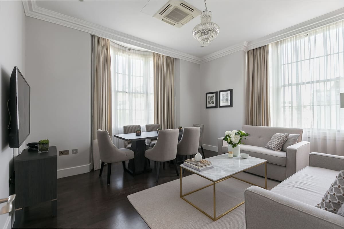 Un salon moderne comprenant un coin repas, un canapé, une table basse et un téléviseur.