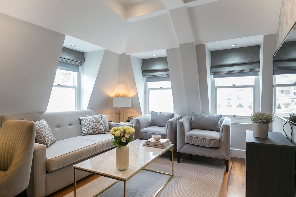 Un salon moderne comprenant un canapé, des fauteuils, une table basse et une lampe.