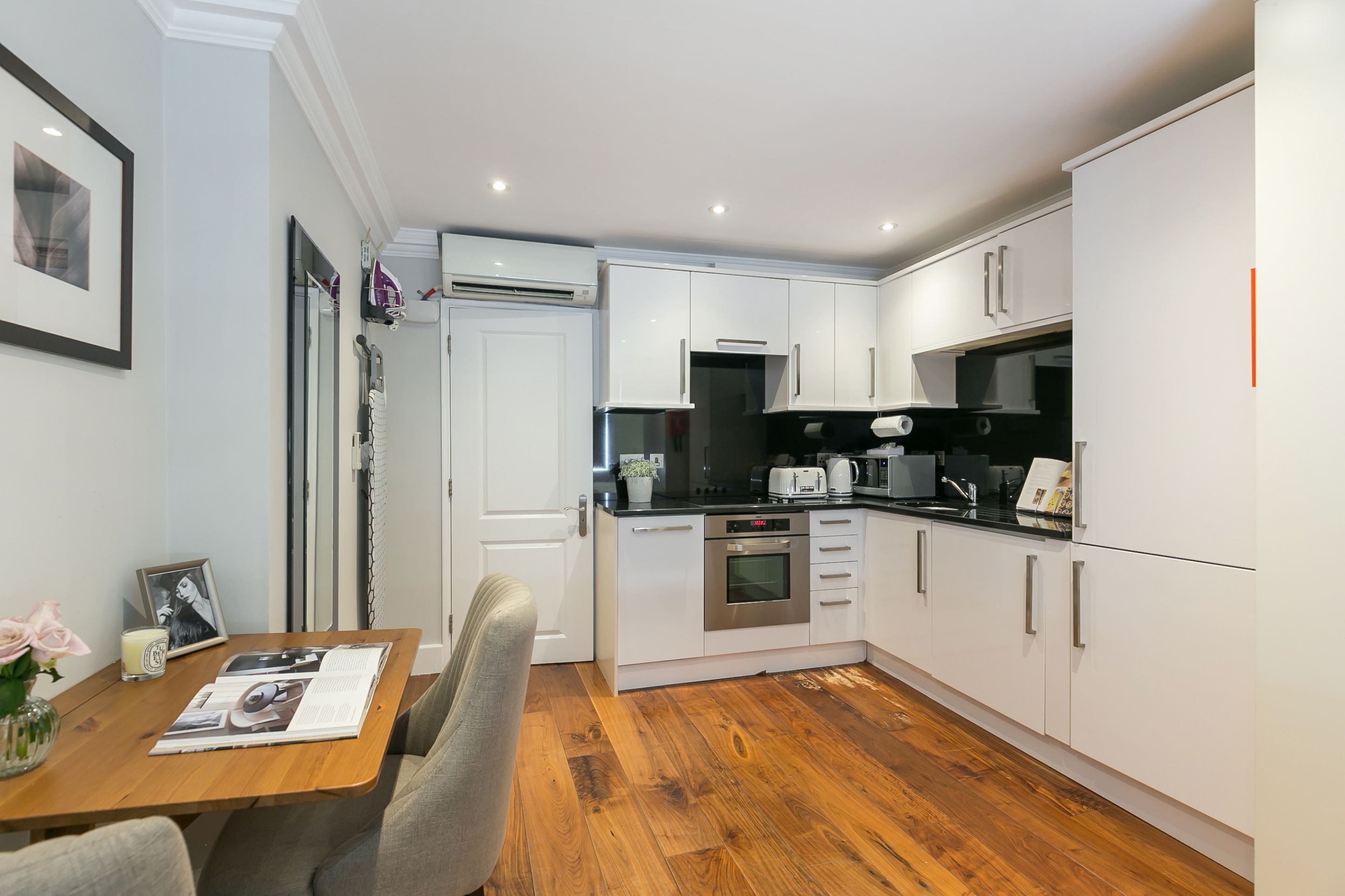 A modern kitchen with white cabinets, stainless steel appliances, and a wooden dining table with chairs.
