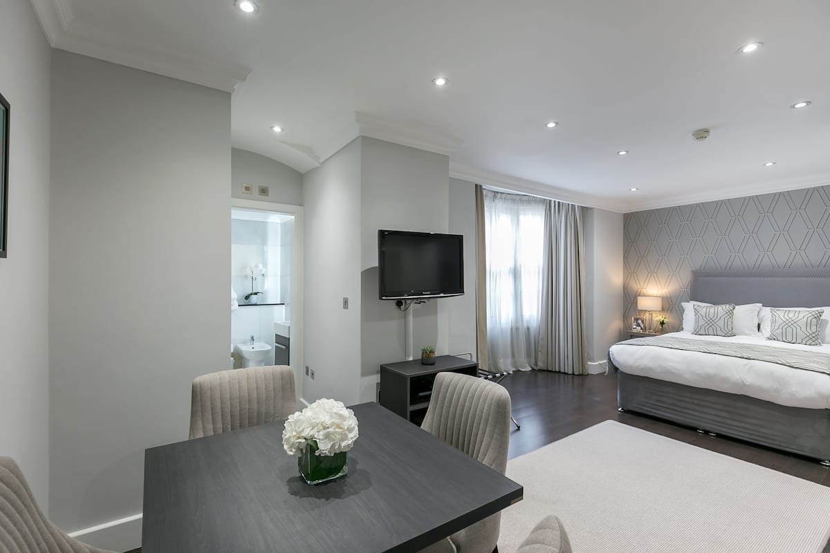 Une chambre moderne avec un grand lit, une télévision et un coin repas comprenant une table et des chaises.