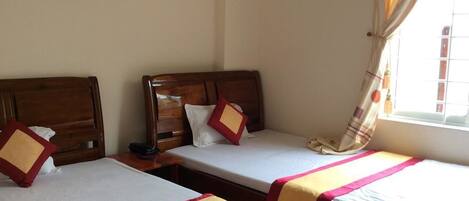 Una habitación con dos camas individuales, cabeceras de madera, ropa de cama blanca y un cuadro en la pared.