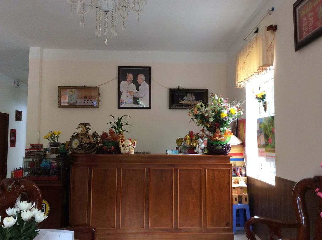 Una zona de recepción con mostrador de madera, cuadros en la pared y un gran arreglo floral.