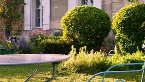 A garden with a metal table and chairs, surrounded by well-maintained bushes and flowering plants. - La Hourqueyre (Saint-Yzans-de-Medoc)