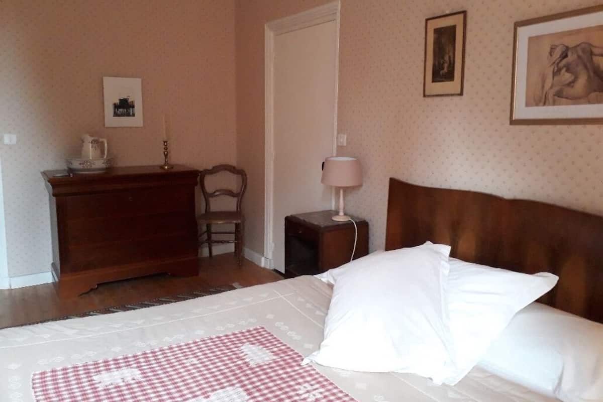 Un dormitorio con cama, cómoda, mesita de noche y una puerta.