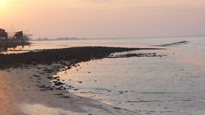 A beach with a rocky shoreline and a pier with buildings. - La Hourqueyre (Saint-Yzans-de-Medoc)
