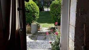 An entrance to a property with a stone pathway leading to a garden area with green bushes and pink flowers. - La Hourqueyre (Saint-Yzans-de-Medoc)