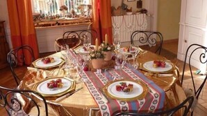 A dining table set for six with gold tablecloths and white plates, surrounded by black metal chairs. - Les Jardins de L'hacienda (Tarare)