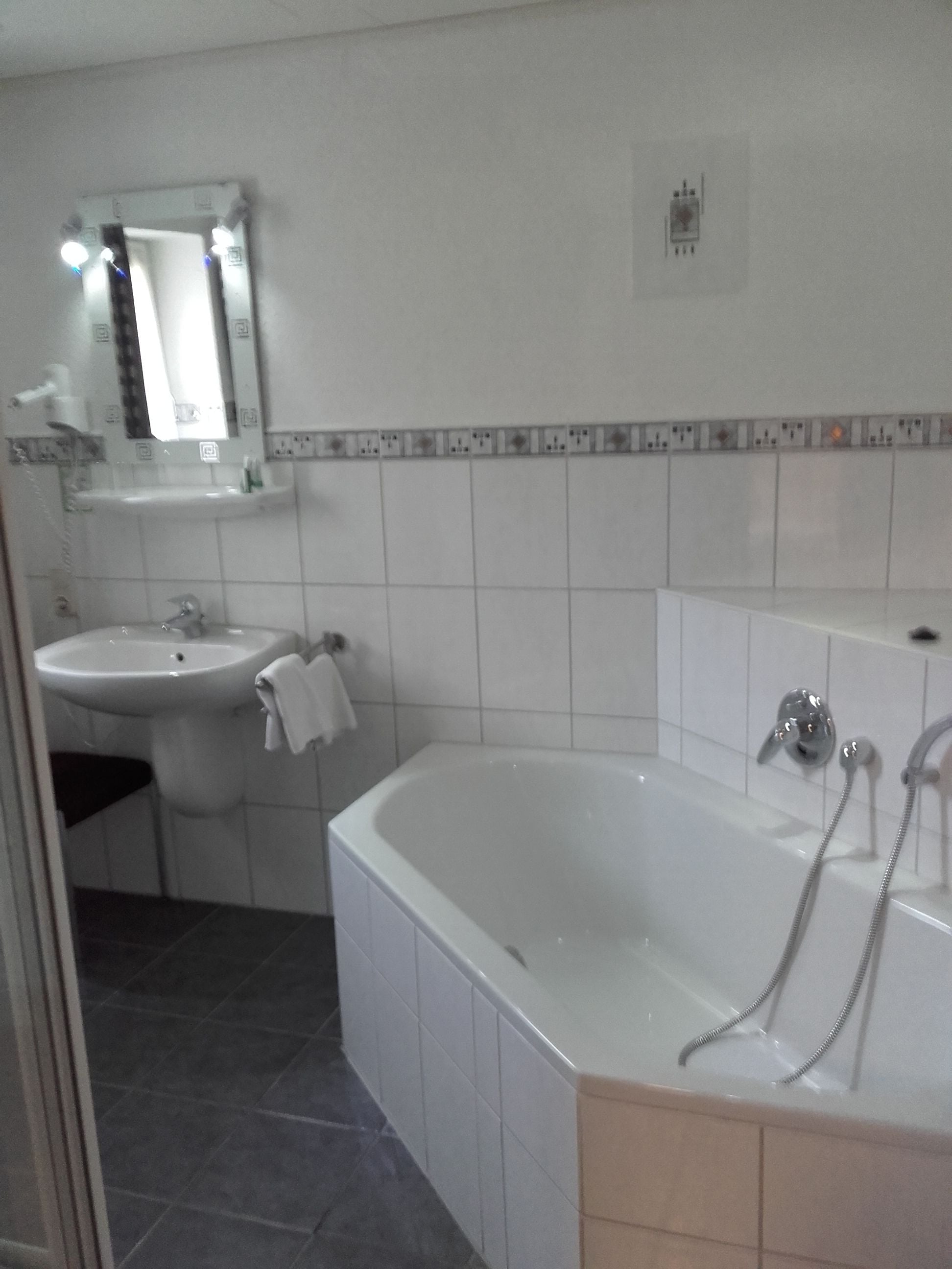 Een badkamer met een badkuip, een wastafel en een spiegel.