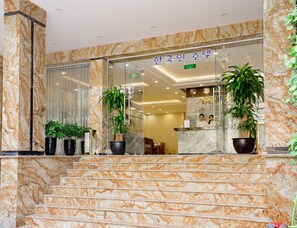 A hotel lobby with marble flooring, a reception desk, and potted plants. -  K Business 2 Hotel My Dinh (Hanoi)