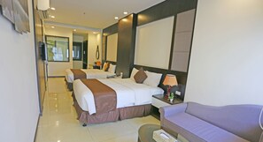 Habitación de hotel con dos camas, un sofá, un televisor y una lámpara.