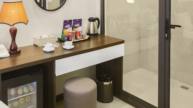 A hotel bathroom with a shower, a mirror, a coffee maker, and toiletries on the counter. - Blubiz Hotel My Dinh Song Da (Hanoi)