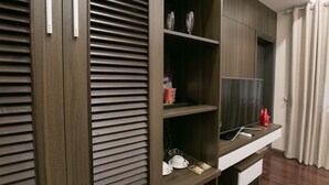 A modern living room with a built-in entertainment unit, a flat-screen TV, and a seating area with a coffee table. - Blubiz Hotel My Dinh Song Da (Hanoi)