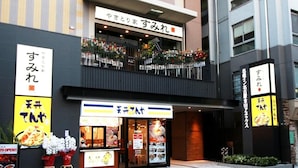 Un restaurant à la façade noire, doté d’un balcon orné de fleurs et d’une enseigne en japonais.