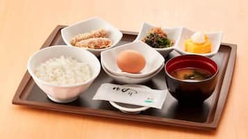 Ein Tablett mit verschiedenen japanischen Speisen, darunter Reis, Ei, Suppe und weitere Zutaten.