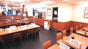 Un restaurant avec des tables et des banquettes en bois, un espace cuisine et un comptoir.