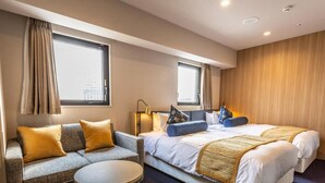 Une chambre d’hôtel avec un canapé, une table ronde et un lit avec deux oreillers.