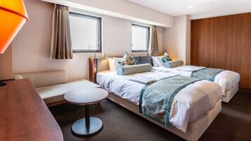 A hotel room with two beds, a sofa, a small round table, and a lamp.