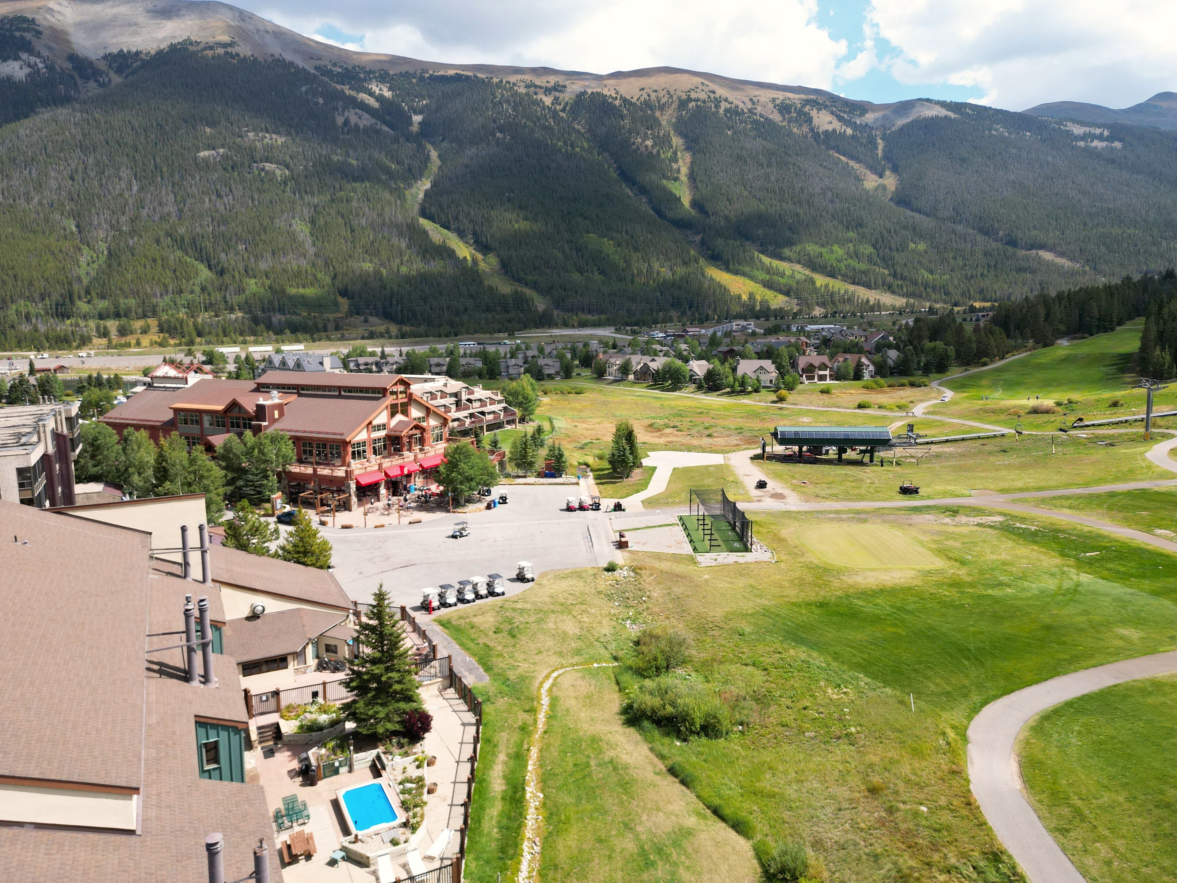 Eine Berglodge mit Pool, Gästezimmern und einem Skiliftgebiet.