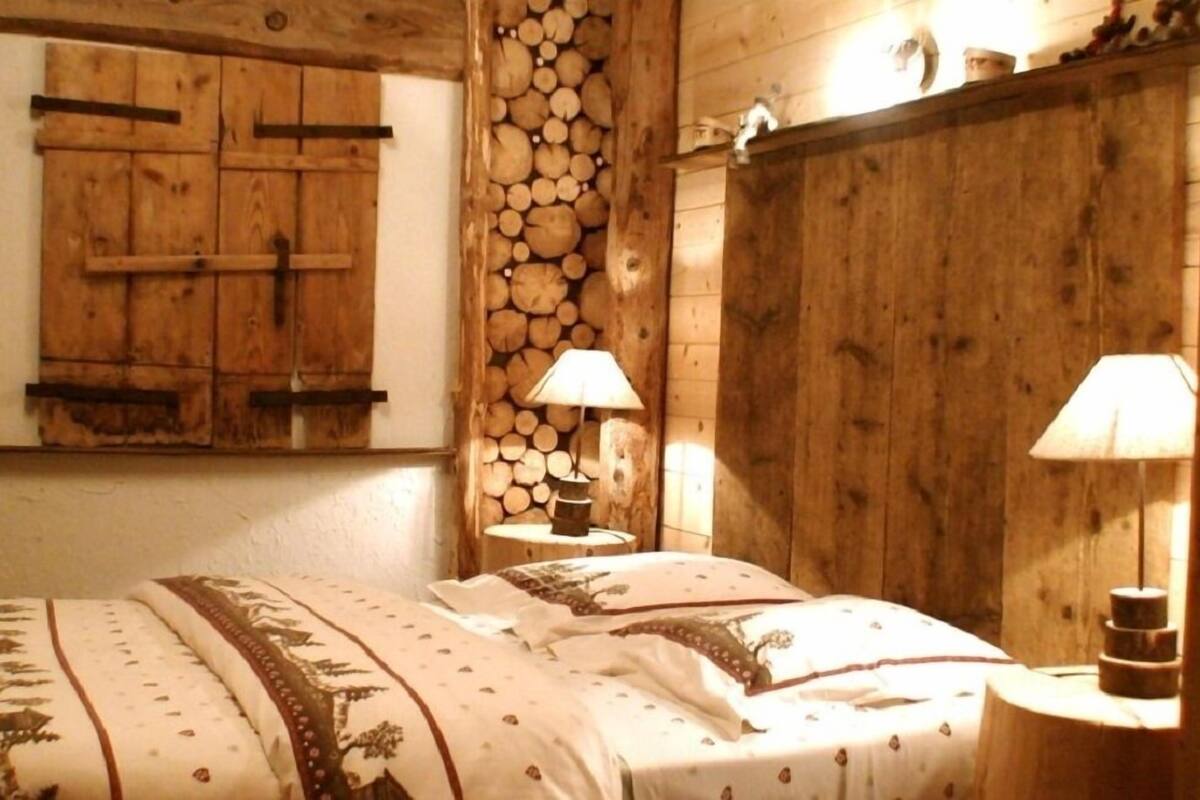 Ein rustikaler Holzraum mit einem Bett, zwei Nachttischen und einer Wand aus gestapelten Baumstämmen.