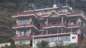 A multi-story building with balconies, large windows, and a flag.