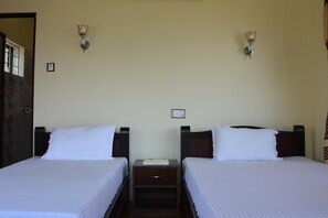Een hotelkamer met twee enkele bedden, een nachtkastje met een boek en twee wandlampen.