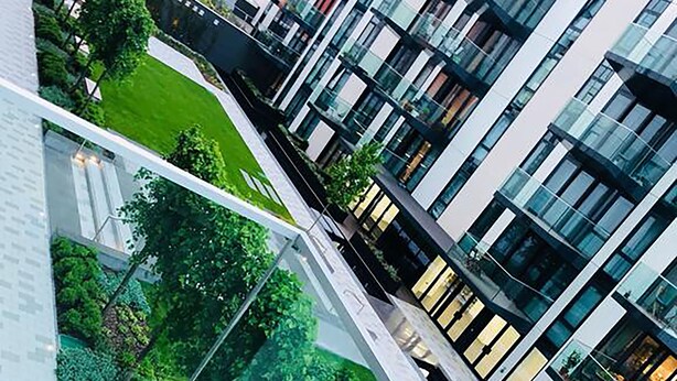 A modern building with a glass facade, surrounded by greenery and a clear sky. - Green Diamond by Creatick Apartments (Brighton)