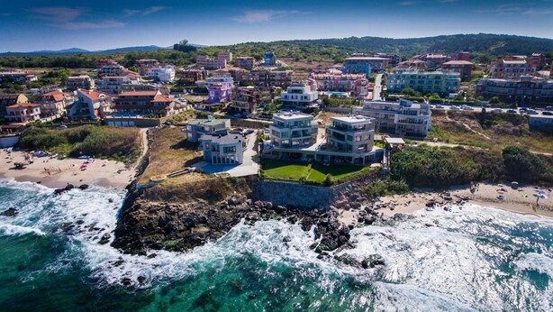A coastal town with modern buildings, a beach, and rocky coastline. - Hotel Sunny (Sozopol)
