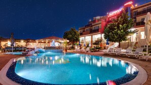 A swimming pool with lounge chairs and a bar in the background. - Hotel Sunny (Sozopol)