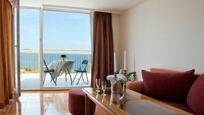 A hotel room with a balcony, a table with glasses, a candelabra, and a red sofa. - Hotel Sunny (Sozopol)