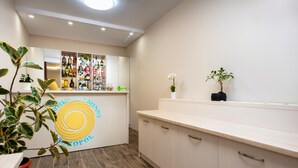 A modern bar area with a counter, shelves of liquor bottles, and potted plants. - Hotel Sunny (Sozopol)
