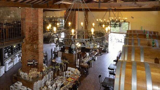 A spacious interior with exposed wooden beams, a large chandelier, and various tables and chairs. - La Corte Medicea (Montepulciano)