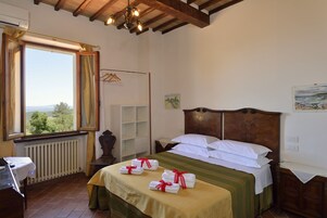 A neatly arranged bedroom with a bed, a radiator, a window with curtains, and a view of the outdoors.