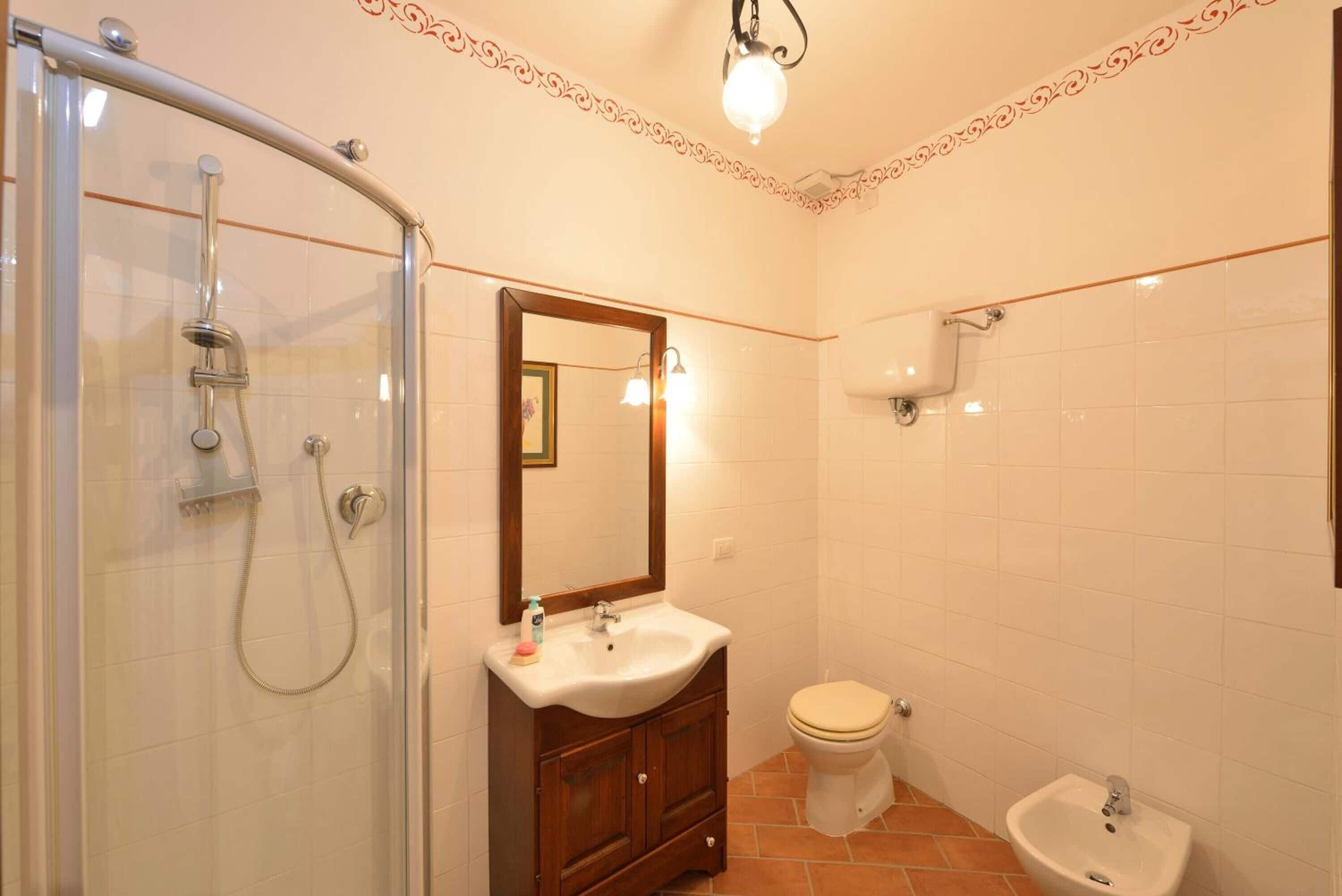 Een badkamer met een douche met glazen wand, een wastafel met spiegel erboven, een toilet en een bidet.