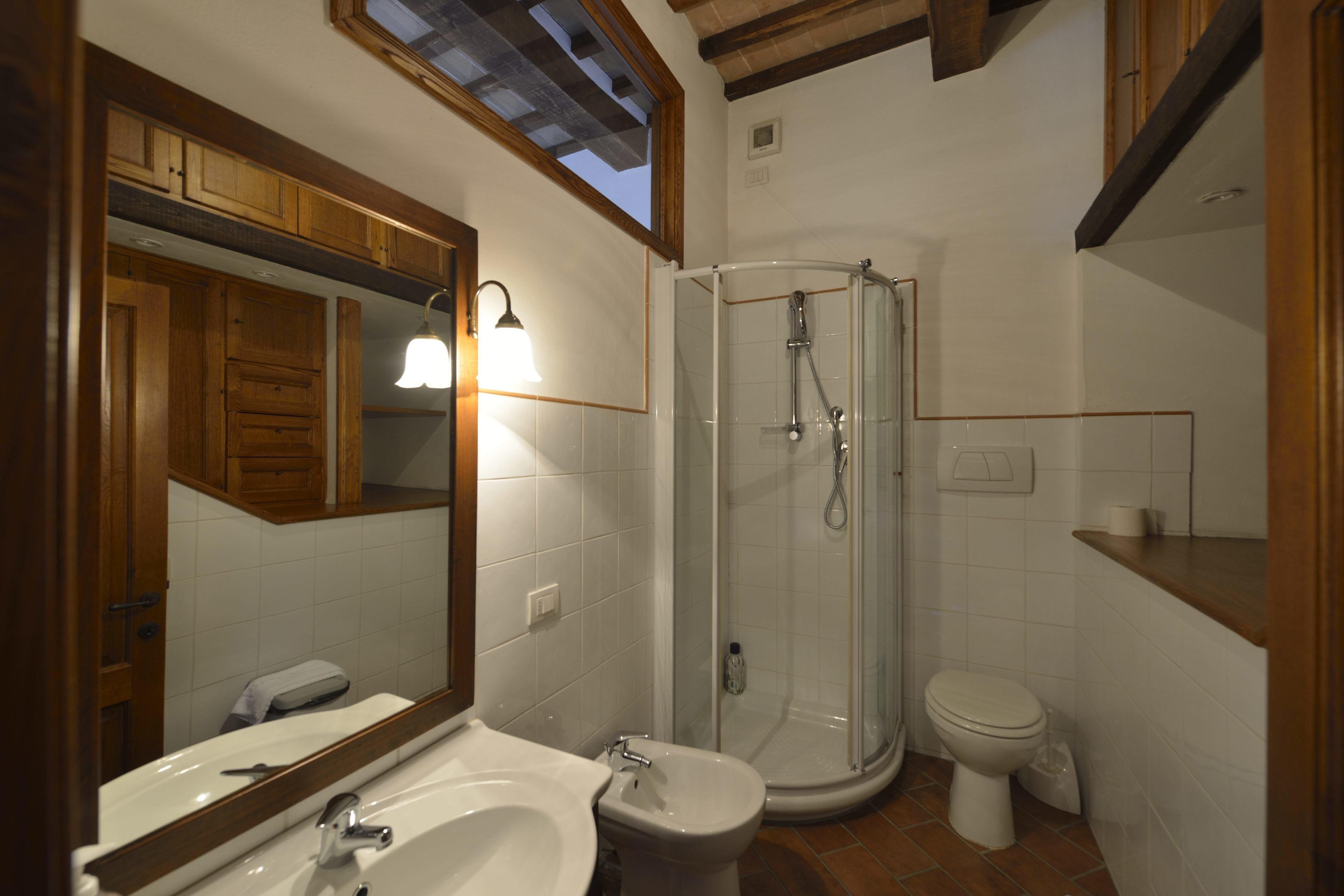 A bathroom with a shower, toilet, sink, and mirror.