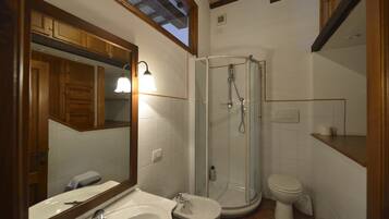 A bathroom with a shower, toilet, sink, and mirror.