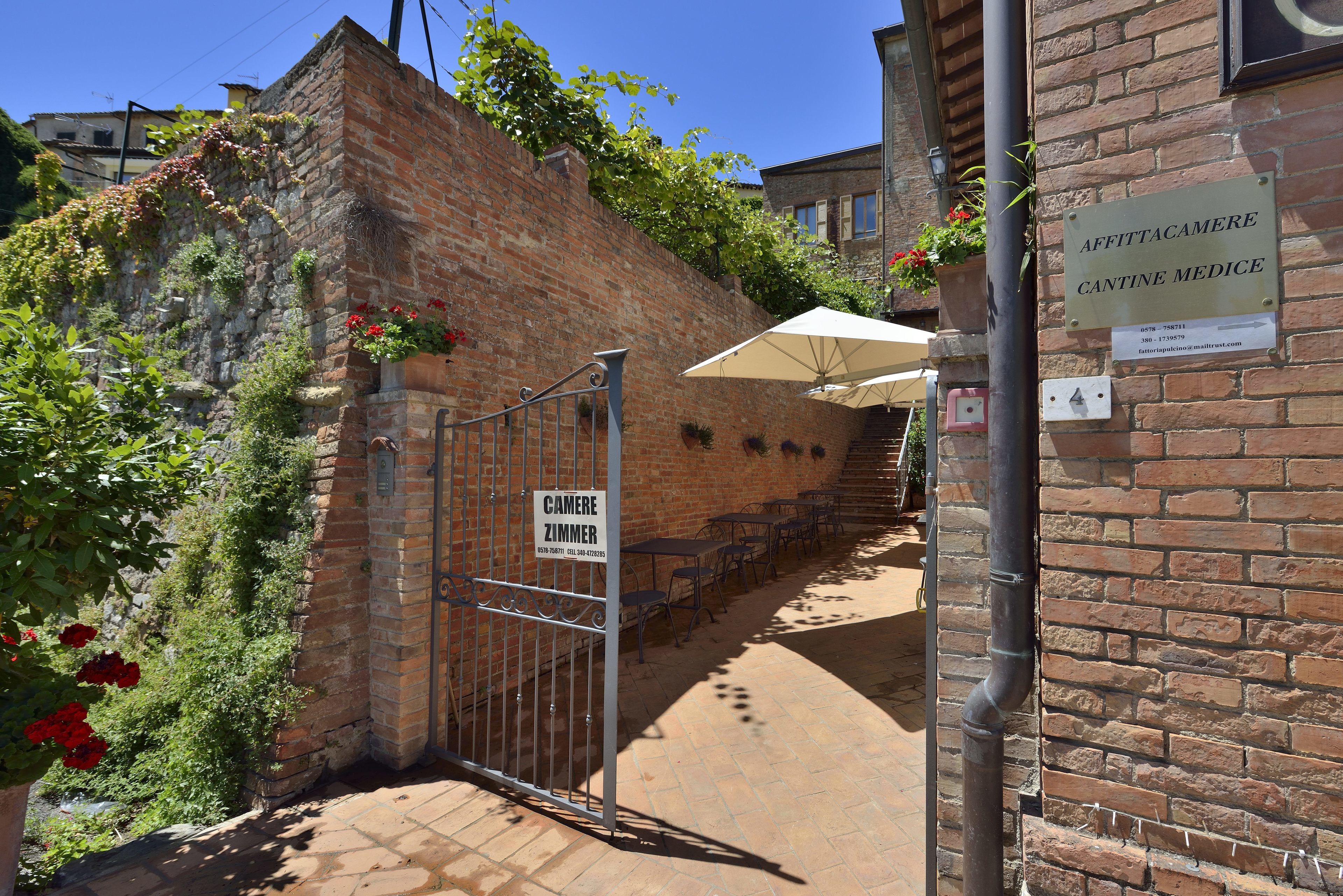 Un bâtiment en briques avec une enseigne indiquant « AFFITTACAMERE CANTINE MEDICE » et un portail portant l’inscription « CAMERE ZIMMER ».
