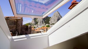 A skylight with a view of rocky mountains and buildings.