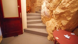 A staircase leading to a room with a wooden door, a small table with decorative items, and a chair.