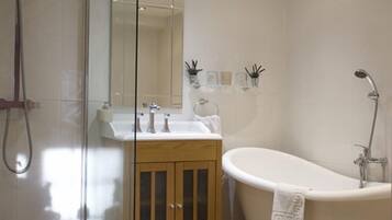 Un baño moderno con cabina de ducha de vidrio, una bañera independiente y un mueble de tocador de madera.