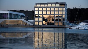 A modern building with a glass facade, a flat roof, and a reflection in the water. - Mandal Hotel (Lindesnes)