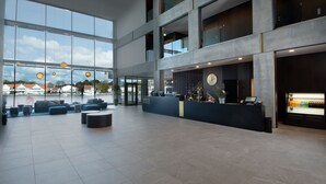A spacious lobby with a reception desk, seating area, and large windows offering views of the city. - Mandal Hotel (Lindesnes)