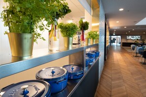 A modern kitchen with stainless steel countertops, blue pots, and potted herbs on shelves. - Mandal Hotel (Lindesnes)