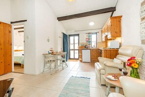 Een gezellige woonkamer met een bank en een eettafel, een keuken met houten kastjes en een klein balkon met uitzicht.