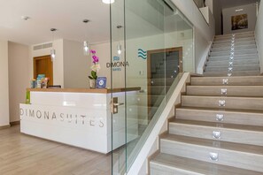 Un comptoir d’accueil portant l’inscription « DIMONASUITES » et un mur en verre.
