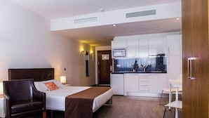 Una habitación de hotel moderna con una cama, una silla, un escritorio y una kitchenette.