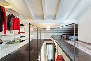 Une chambre de style loft moderne, dotée d’un lit superposé, d’étagères intégrées et d’un luminaire suspendu.