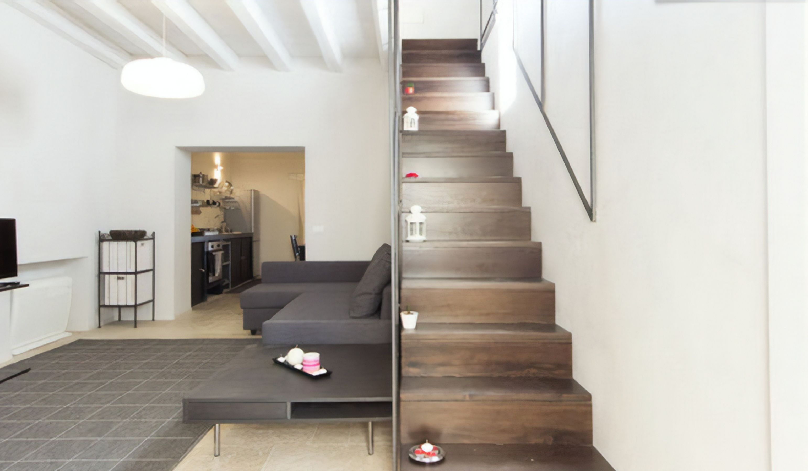 Ein modernes Wohnzimmer mit einem grauen Ecksofa, einem Couchtisch und einer Treppe mit Holzstufen.