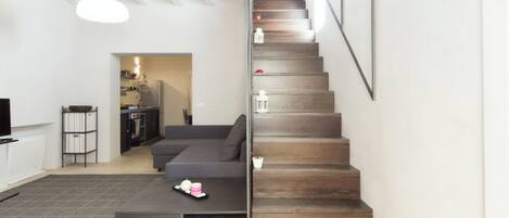 Ein modernes Wohnzimmer mit einem grauen Ecksofa, einem Couchtisch und einer Treppe mit Holzstufen.