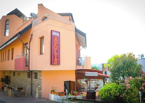 A hotel with a prominent vertical sign, a balcony, and a small outdoor seating area. - Apolis (Sozopol)