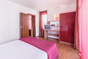 A hotel room with a bed, a desk with a TV, and a wardrobe. - Apolis (Sozopol)